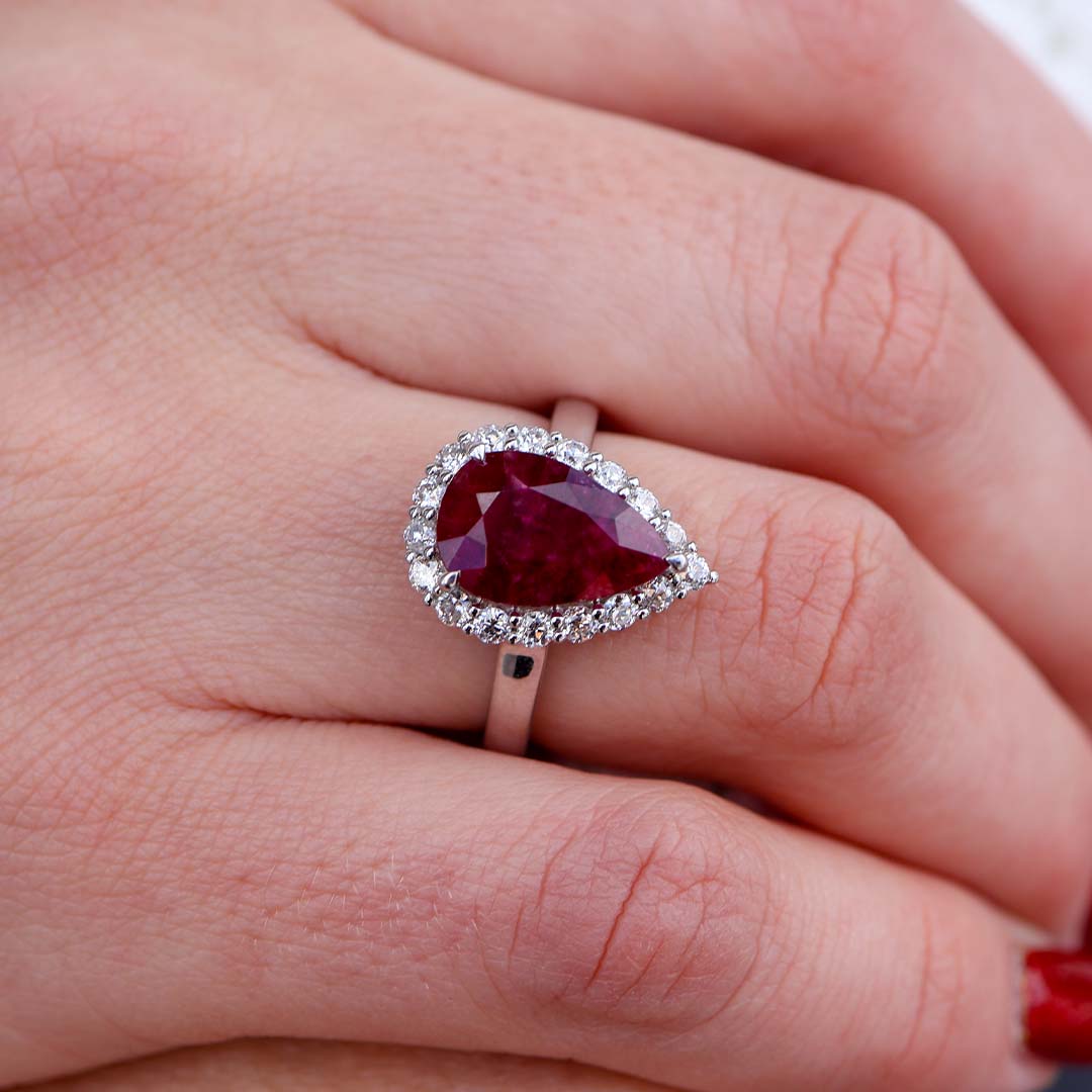 Woman Wearing Pear Shaped Red Emerald (Red Beryl) Ring with a Diamond Halo