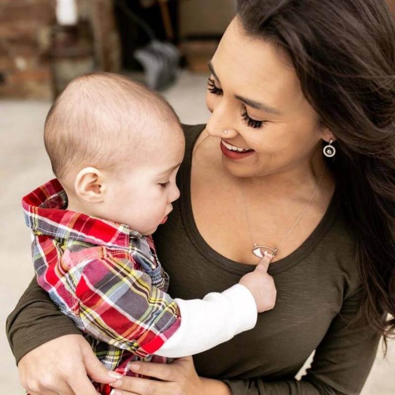 Woman holding baby wearing diamond mountain necklace - Park City Jewelers.