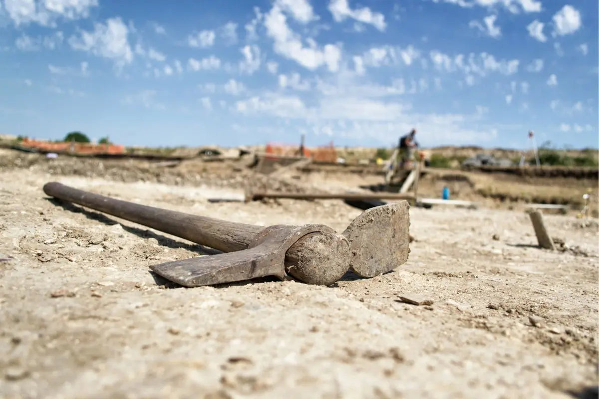Pickaxe sitting on the ground of a dig.