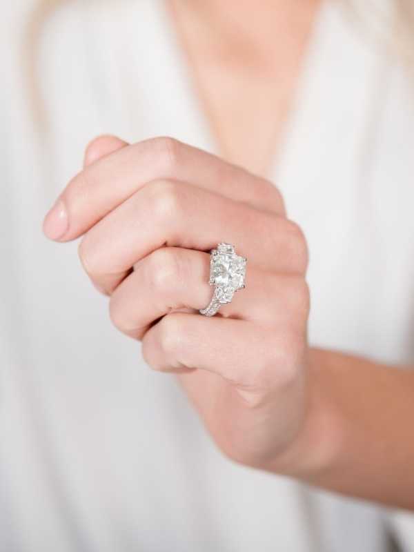 Woman's hand wearing a large princess cut diamond ring