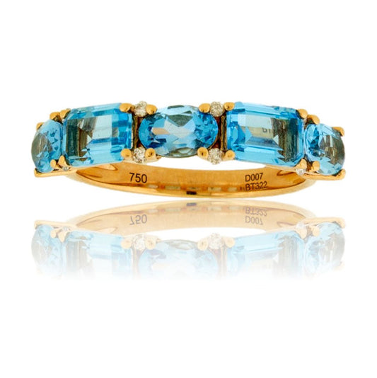 Front view of a five-stone blue topaz ring in 14K yellow gold, featuring an alternating pattern of oval and emerald-cut stones with small diamond accents.