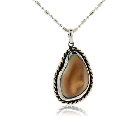 A custom-fit elk ivory pendant with a two-tone setting, featuring a 14K yellow gold braided halo around a darkened sterling silver bezel.
