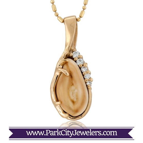 An asymmetrical elk ivory pendant in 14K yellow gold, with a sculptural antler on one side and a river of graduated diamonds on the other.