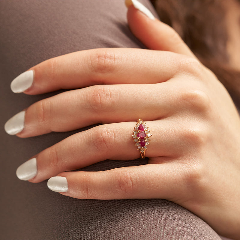 Elegant woman wearing a stunning yellow gold ring featuring a princess cut Red Emerald, part of Park City Jewelers' exclusive Red Beryl Collection