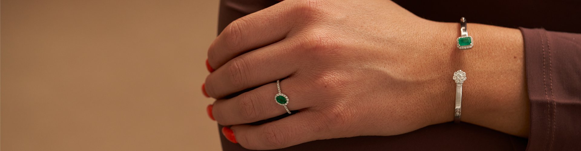 Stylish woman showcasing a radiant emerald ring and matching bracelet from the Park City Jewelers' Emerald Collection.