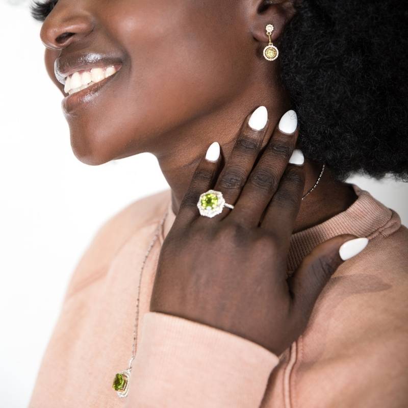 Woman wearing peridot ring, earrings, and necklace