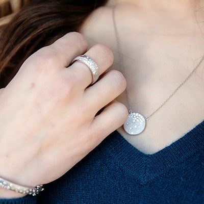 Woman wearing white gold and diamond confetti necklace, ring, and bracelet