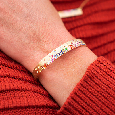 Woman wearing gold rainbow confetti bracelet