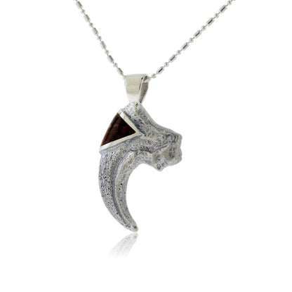 A sterling silver T-Rex claw pendant with a rugged, textured finish, featuring a triangular inlay of reddish-brown dinosaur bone at the top.
