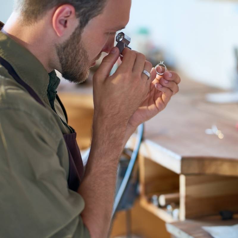 Jeweler looking at ring through loop