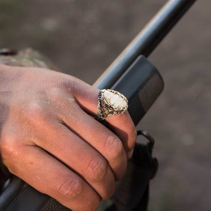 Man wearing elk ivory ring while holding rifle