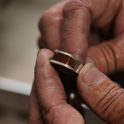 Jeweler Holding Gold and Dinosaur Bone Inlay Ring