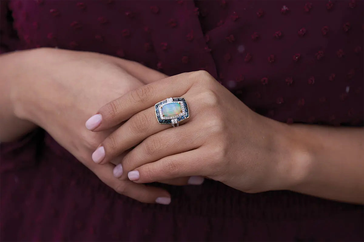 Woman Wearing opal Ring with Blue Topaz Halo from Park City Jewelers