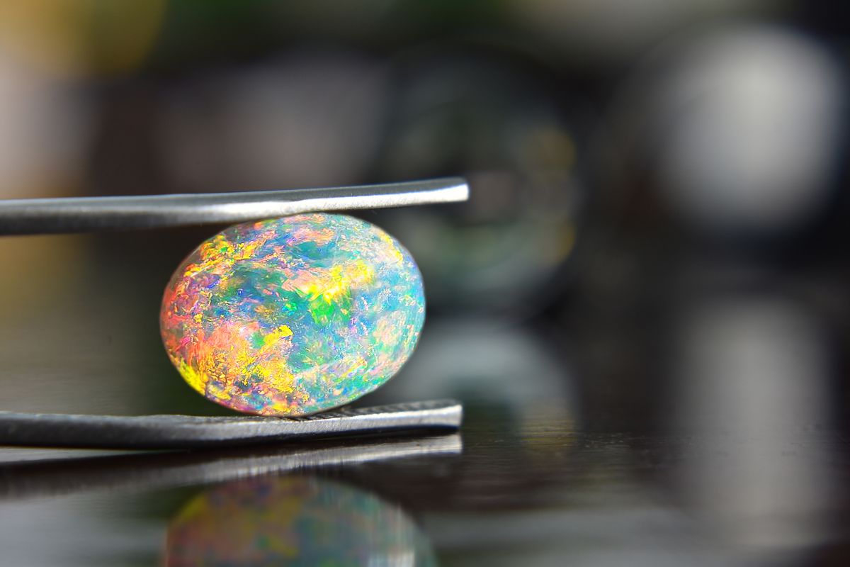 Opal Gemstone Held Between Tweezers.