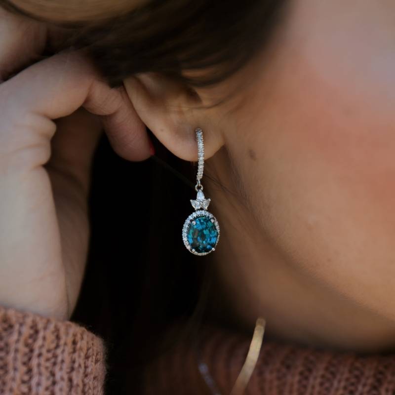 Woman wearing diamond halo blue zircon earrings - Park City Jewelers. 