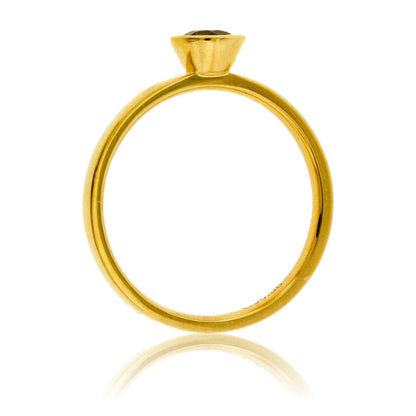 Side profile of a bezel-set alexandrite solitaire ring, showing the clean lines of the 14K yellow gold setting and band.