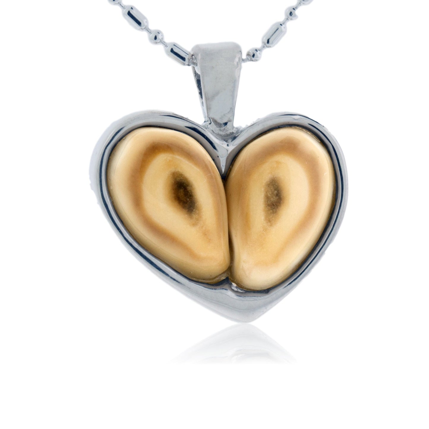 A heart-shaped pendant made from two polished elk ivories, bezel-set in sterling silver and hanging from a ball chain.