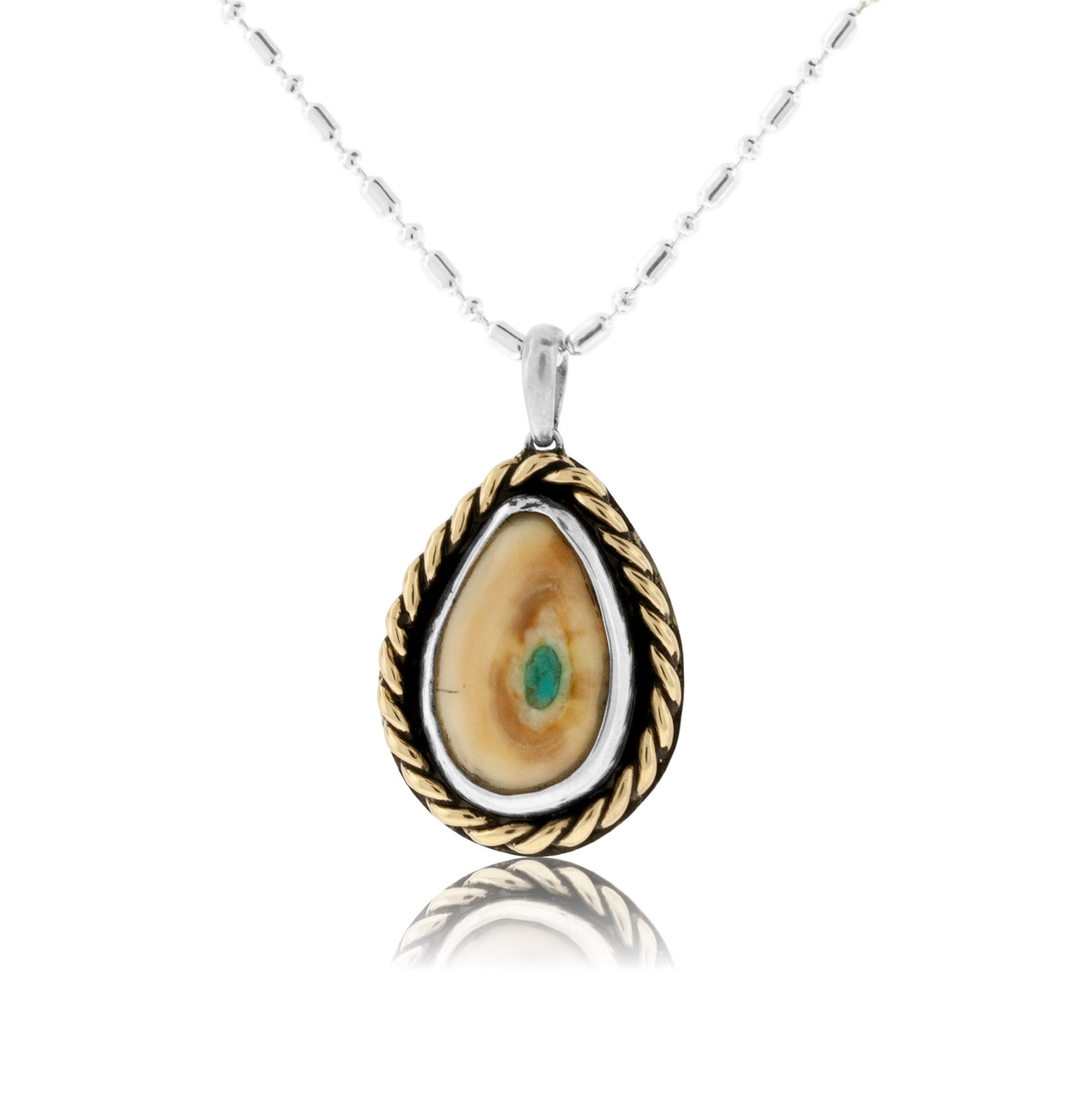 A two-tone elk ivory pendant with a sterling silver bezel and a 14K yellow gold braided frame, featuring a small round turquoise inlay in the center of the ivory.